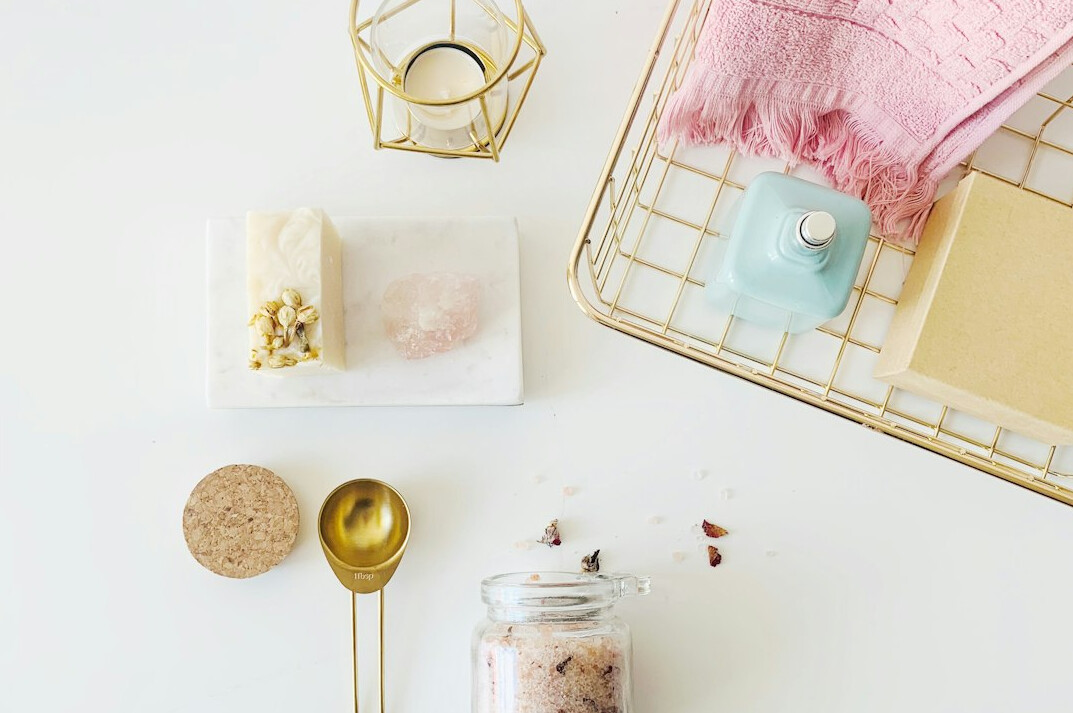 Bowl of bath salt and skincare accessories on a light surface